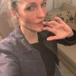 Foto einer schmalen Frau mit einer Hand an den Lippen