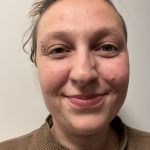 Foto einer lächelnden Frau mit braunem Pullover