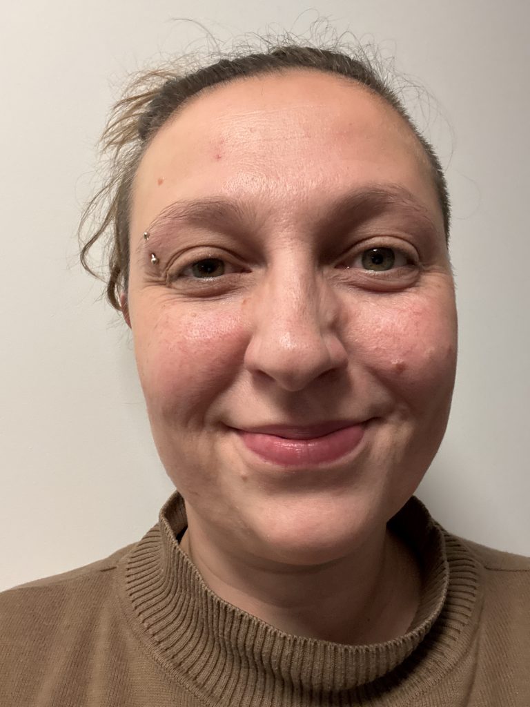 Foto einer lächelnden Frau mit braunem Pullover